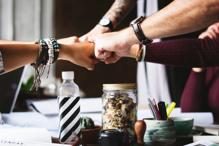 close-team-of-people-fist-bumping-each-other