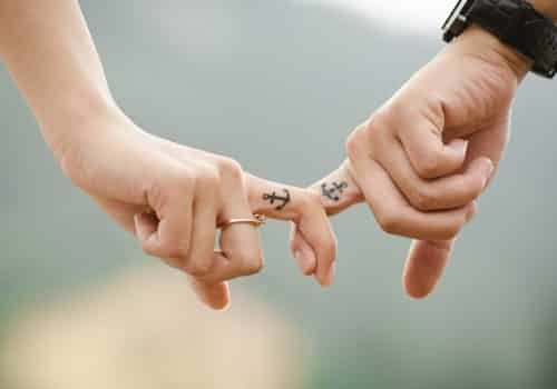 happy-couple-with-matching-tattoos-locking-fingers
